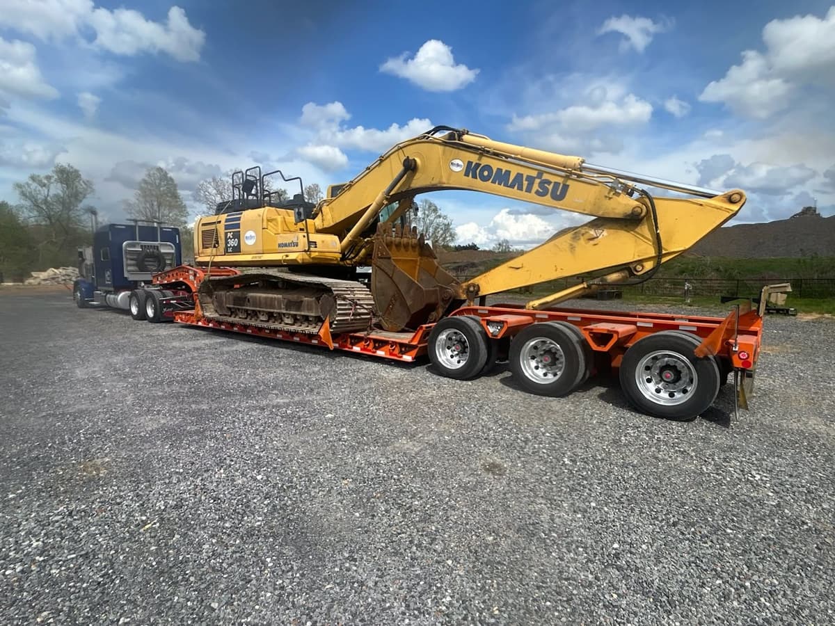 Blue Peterbilt with multi-axle trailer hauling a Komatsu excavator