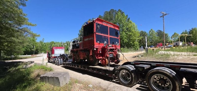 Red railcar mover loaded on an AJC lowboy in Georgia
